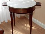 une petite table avec un plateau en marbre sur un plancher en bois