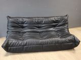 a black leather futon sofa sitting on top of a hard wood floor