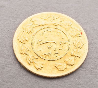 a close up of a gold coin on a gray surface