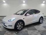 Le SUV Tesla blanc est garé sur un sol en carrelage à damier.