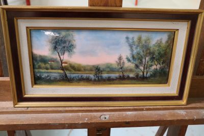 tableau représentant un paysage avec des arbres et une rivière, dans un cadre doré