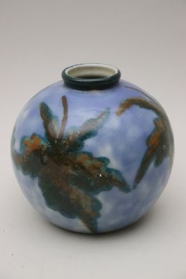 un vase bleu et brun posé sur une surface blanche