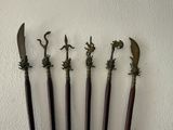 four old metal and wood handled knives on a white wall