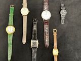 four different watches are lined up on a black surface