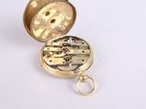 a gold pocket watch with a keychain on a white surface