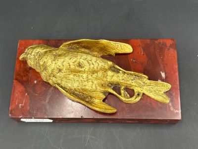 sculpture en laiton représentant un oiseau, posée sur un bloc de bois posé sur une table