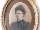 une vieille photo d'une femme en robe noire, dans un cadre doré
