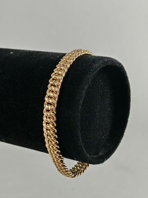 a close up of a gold chain bracelet on a black ring holder