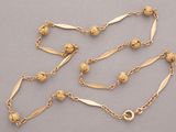 a close up of a gold chain with beads on it