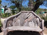 a wooden bench made out of logs on the side of the road