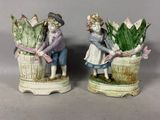 deux figurines représentant un garçon et une fille avec un panier de fleurs