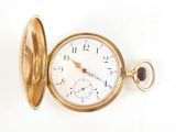 a gold pocket watch sitting on a white surface