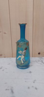 un vase en verre bleu sur lequel est représenté un garçon
