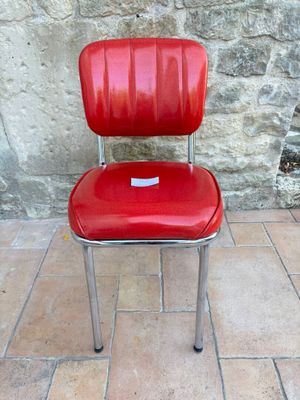 a red chair that is sitting in front of a stone wall