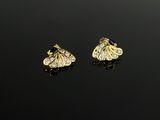 une paire de boucles d'oreilles en or et diamants sur une surface noire