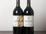 two bottles of red wine sitting on top of a wooden table
