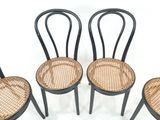 trois chaises noires avec une assise en osier et une assise en bois