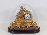 a gold clock under a glass dome on a table