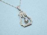 a close up of a silver necklace with a bird in a cage