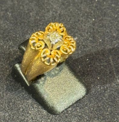 a gold ring with a diamond in it on a black surface