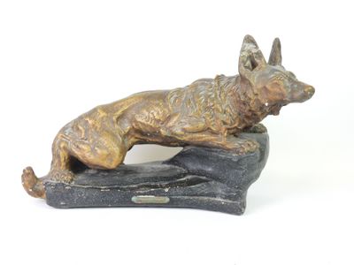 statue of a dog laying on a rock on a white background