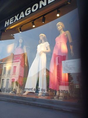 de nombreux mannequins dans la vitrine d'un magasin de vêtements