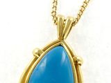 a gold necklace with a blue tear shaped stone on a chain