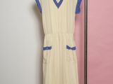 beige and blue dress hanging on a hanger against a pink wall