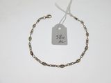 a silver bracelet with a tag on it on a white table