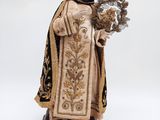 une statue représentant une femme tenant un bouquet de fleurs, posée sur un socle en bois