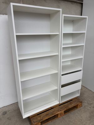 Deux bibliothèques blanches sont empilées sur des palettes dans un entrepôt