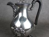 une cafetière ancienne en argent avec une poignée noire sur fond gris