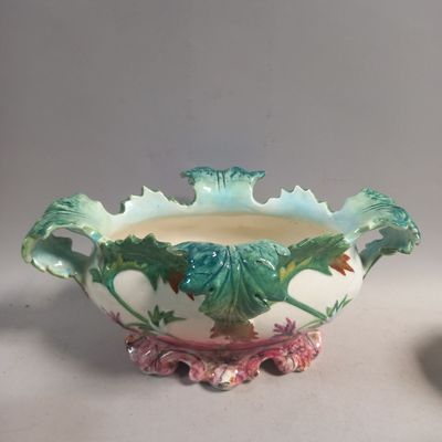 un vase orné d'un motif de feuilles vertes, à côté d'un bol