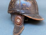 an old helmet is sitting on a blue surface with a metal hook