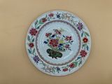une assiette décorée d'une composition florale, accrochée au mur
