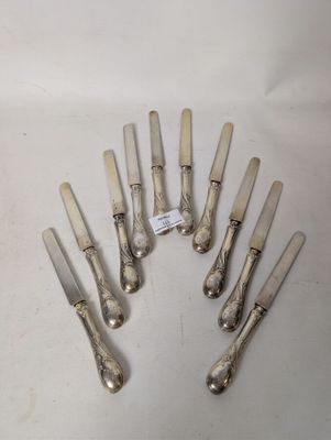 eight silverplated knives are arranged in a circle on a white surface