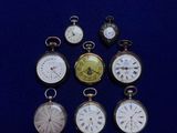 Plusieurs modèles différents de montres de poche sont exposés sur un fond bleu