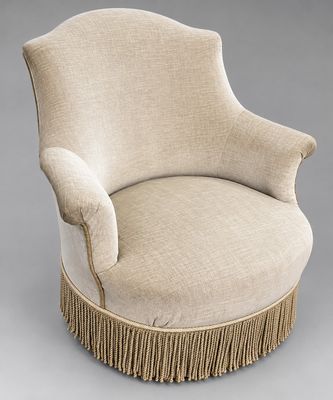 une chaise rembourrée avec des franges sur les pieds