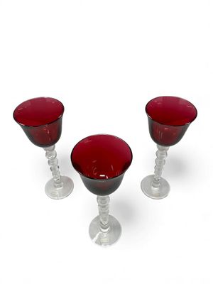 three wine glasses sitting next to each other on a white surface