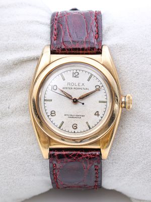 un gros plan d'une montre-bracelet en or posée sur un tissu blanc