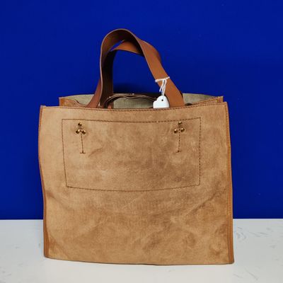 Sac fourre-tout beige à anses en cuir posé sur une table blanche
