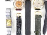 several different types of watches are arranged in a row on a white surface