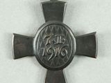 an image of a silver cross with a green stone in the center