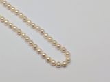 a close up of a pearl necklace on a white surface