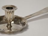 un petit bougeoir en argent posé sur une table blanche
