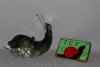 un petit escargot en verre posé à côté d'un petit aimant