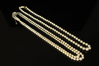 a close up of a white pearl necklace on a black surface