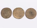 three old coins sitting side by side on a white surface