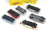 several toy cars are lined up on a white surface with a box in the background
