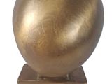 a gold sculpture of a ball on top of a wooden block